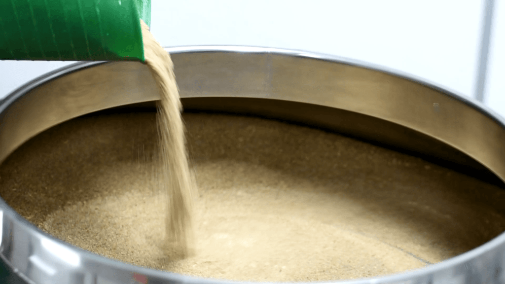 Fine powder being fed into a Farleygreene industrial sieve during powder screening